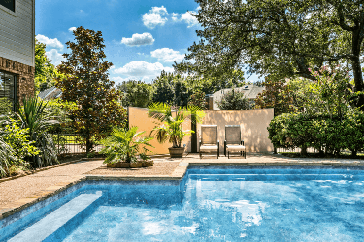 Backyard vinyl liner swimming pool with landscaped garden, lounge chairs, privacy wall and spacious patio